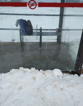 Bus stop shelter bench surrounded by snow