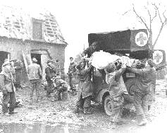 During Operation BLOCKBUSTER, wounded men of the North Shore  Regiment being placed on a jeep ambulance
