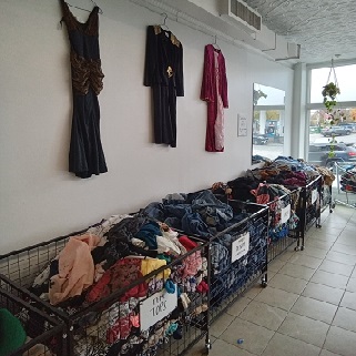 the inside of the store: a row of bins with dresses hanging on the wall
